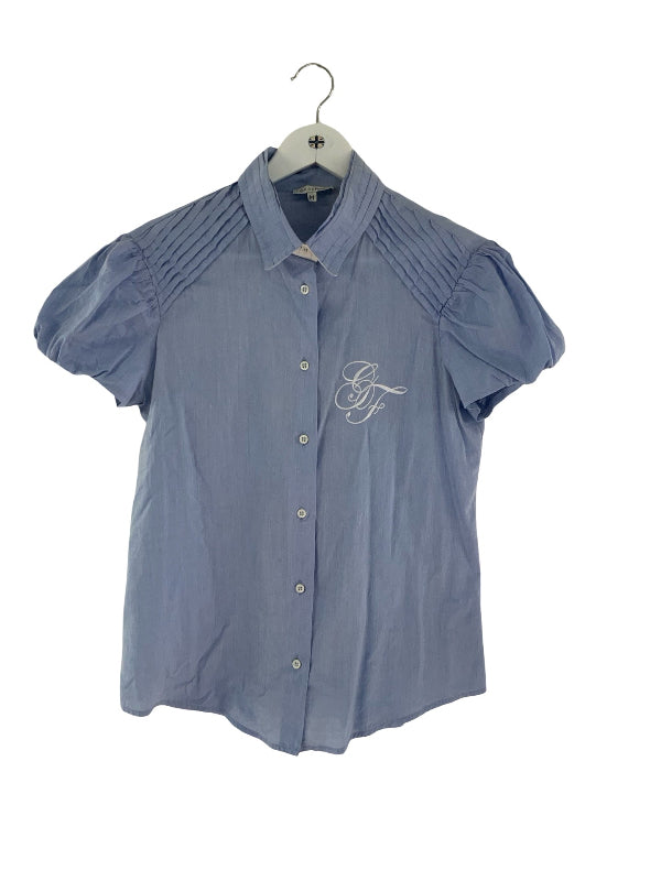 A light blue short-sleeve button-up shirt with pleated shoulders and a white embroidered monogram on the left chest, hanging on a white hanger against a white background.