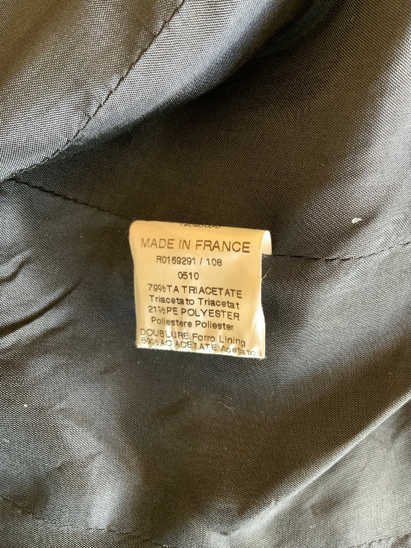 Close-up of an interior fabric tag on dark gray or black quilted clothing, with visible stitching and the text 'MADE IN FRANCE' and material details.