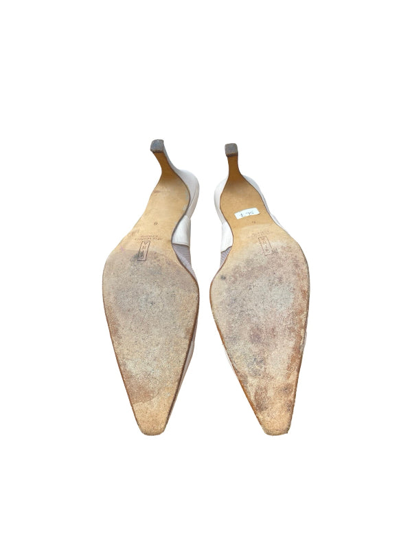 The soles of a pair of pointed-toe slingback pumps, showing a heavily worn, scuffed tan and brown rubber outsole, photographed against a solid white background.