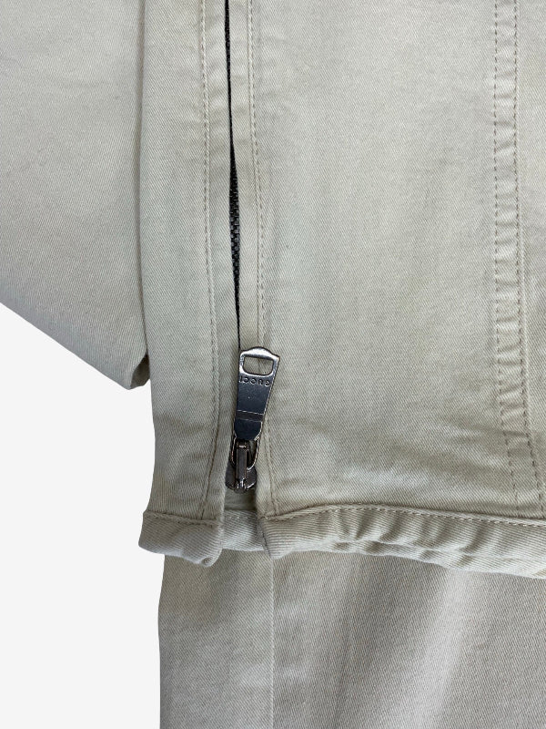 Close-up of a light beige or off-white fabric garment with a silver zipper and a small metal pull tab showing the brand name 'SOLIS'.