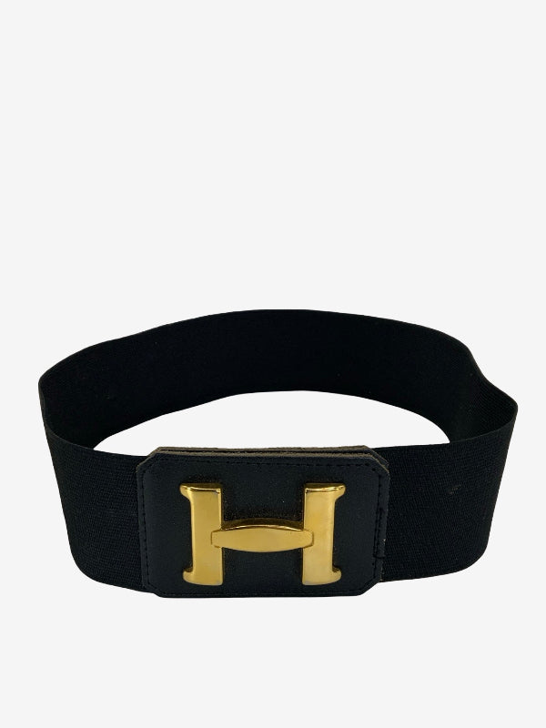 A black elastic belt with a large gold-tone H-shaped buckle, displayed against a plain light gray background.
