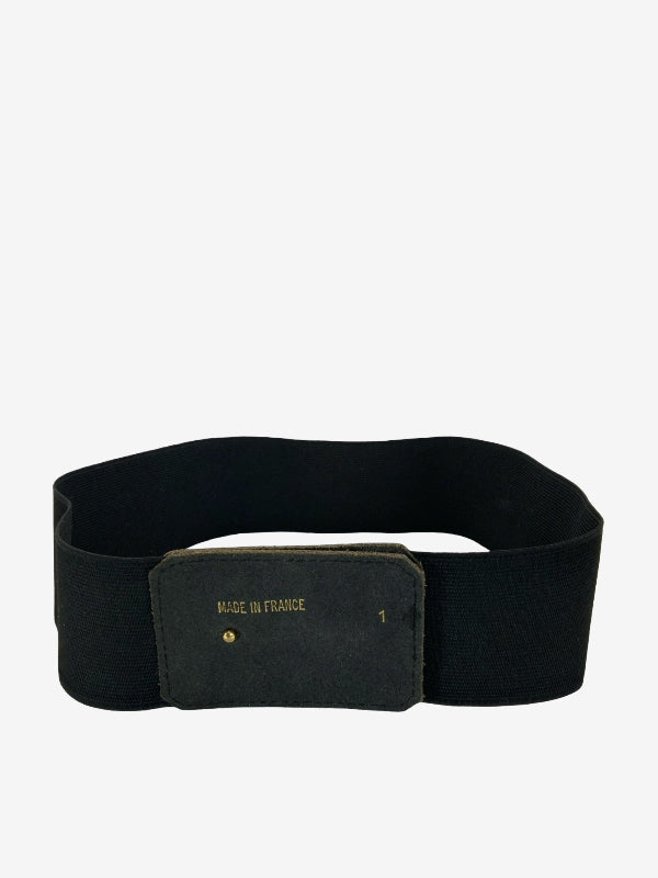 A black elastic belt with a rectangular black buckle featuring gold 'MADE IN FRANCE' text, shown on a plain light gray background.