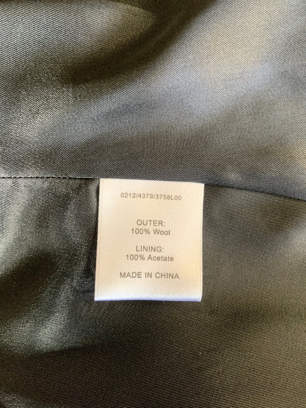 Close-up of a garment's interior label reading 'OUTER: 100% Wool' and 'LINING: 100% Acetate' on a dark gray satin-like fabric background.