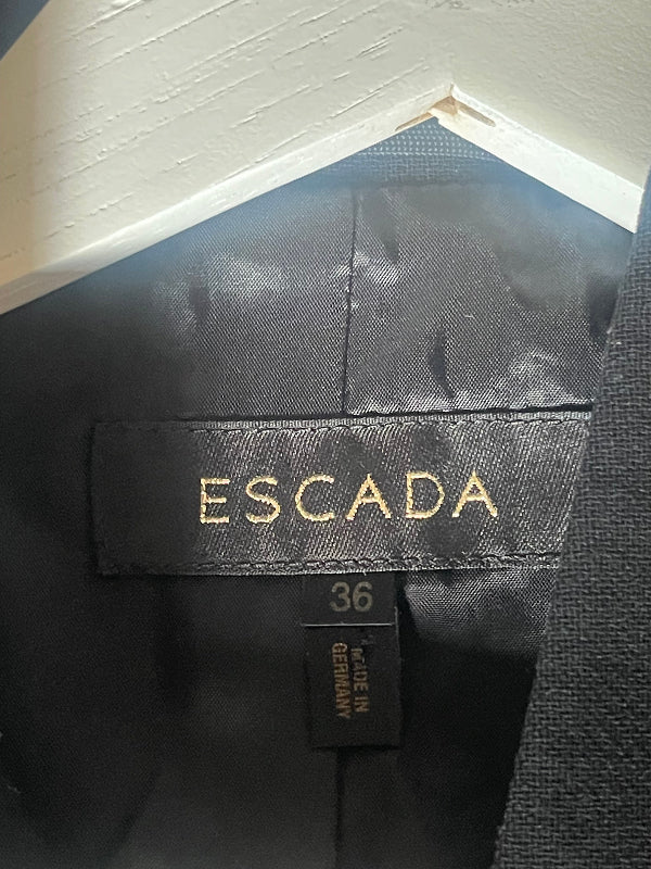 Close-up of the interior neck label of a black Escada garment, showing the gold ESCADA brand name, size 36, and 'Made in Germany' text.