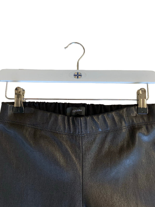 Black leather pants on a white hanger with metal clips, showing the elastic waistband and a small black JOSEPH brand tag.