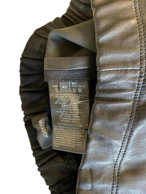 Close-up of a bkack leather garment showing the interior lining, elasticized side seam, and a sewn-in size tag for Joseph. The brand name JOSEPH is clearly visible on the fabric tag.