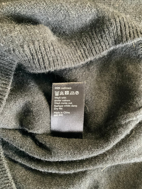 Close-up of a black  garment showing the ribbed collar and a black care label with washing instructions.
