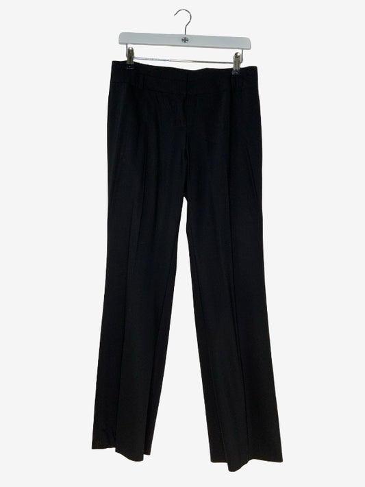 Black wide-leg trousers hanging from a white plastic hanger against a light gray background.