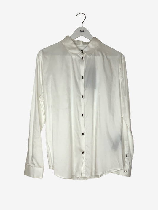 An off-white long-sleeve button-up shirt with a band collar, hanging on a white hanger against a light gray background.