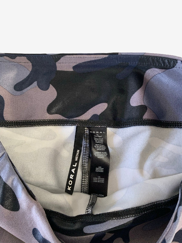 Close-up of a Koral brand garment with a gray, black, and muted purple camouflage pattern, showing the interior lining and a black size tag.