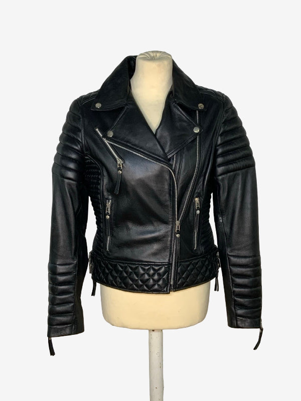 A black leather motorcycle jacket with quilted details on the hem and sleeves, displayed on a cream-colored mannequin torso against a plain white background.