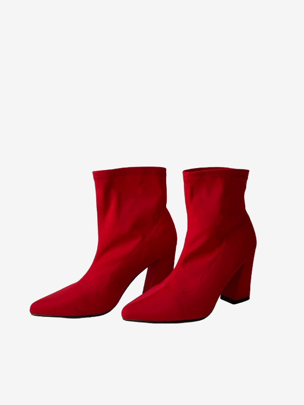 A pair of bright red ankle boots with a pointed toe and a chunky block heel, shown against a plain light gray background.