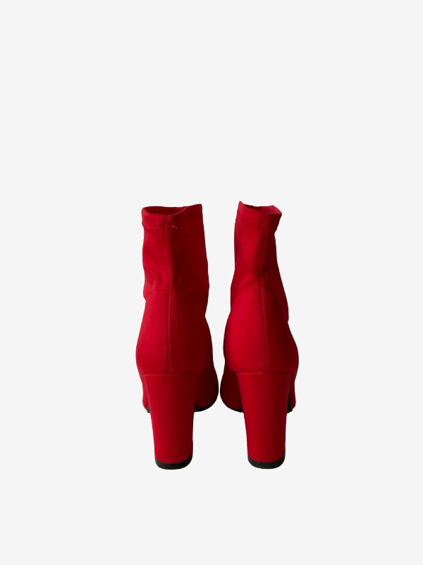 A pair of bright red ankle boots with block heels, shown from the back against a plain white background.