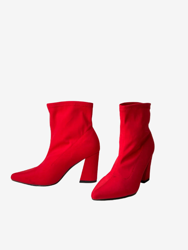 A pair of bright red ankle boots with a block heel and pointed toe, shown from the side against a plain light gray background.
