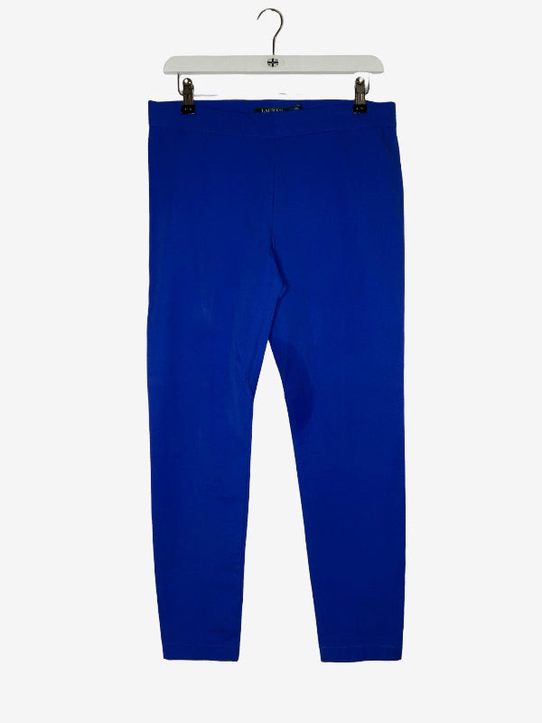 A pair of bright royal blue leggings hanging from a white plastic hanger with black clips against a light gray background.
