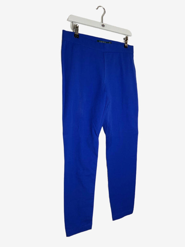 Bright royal blue cropped gabardine stretch pants  hanging from a white plastic hanger against a plain white background.