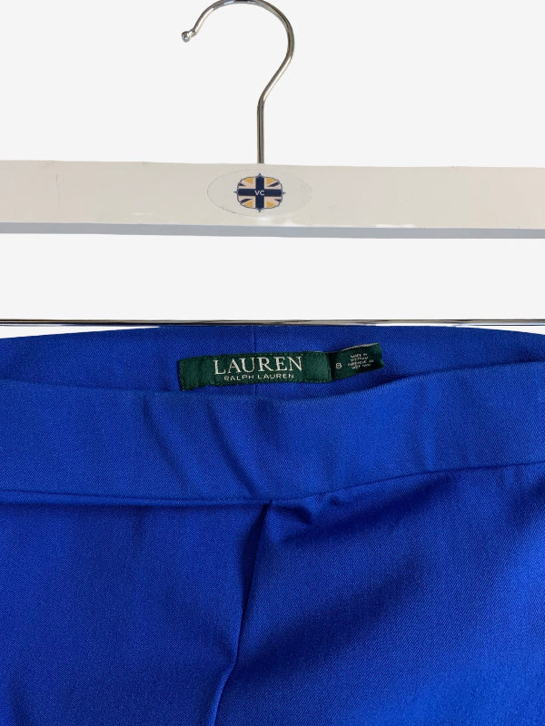 Close-up of a pair of royal blue Lauren Ralph Lauren trousers hanging on a white hanger with a small Union Jack emblem.
