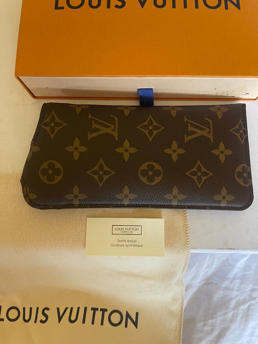 A Louis Vuitton monogram wallet or card holder shown next to its orange box and dust bag, with a small authenticity card in the center.