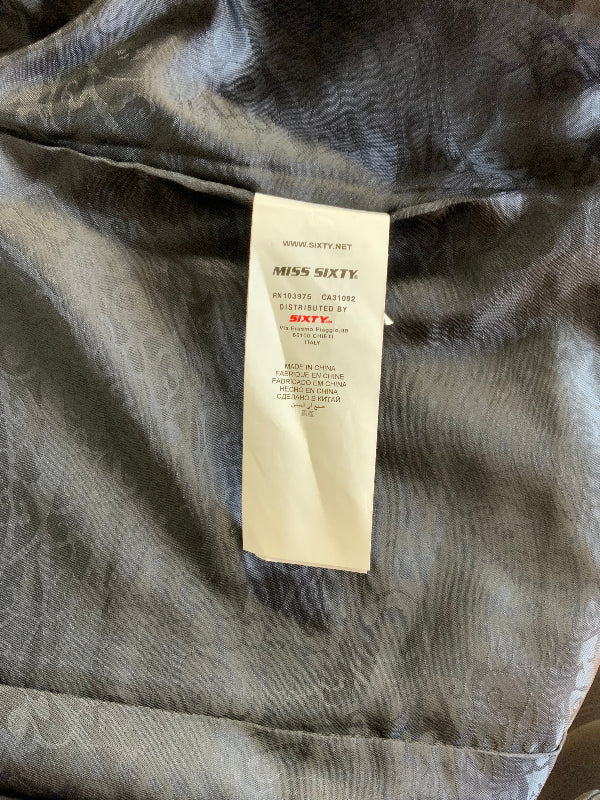 A close-up of a black patterned lining fabric garment with a white paper tag reading MISS SIXTY.
