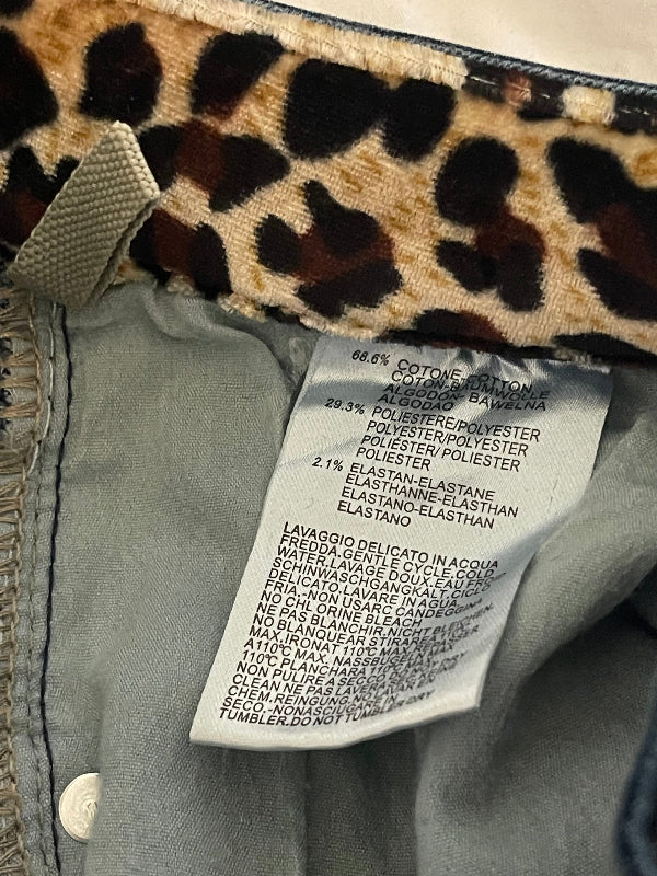 Close-up of the interior waistband of a garment showing a leopard print lining, a white sewn-in care label, and a light gray fabric lining.