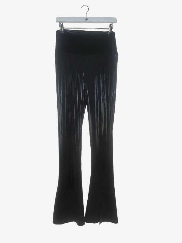Black flared pleated pants hanging from a white hanger against a light gray background.