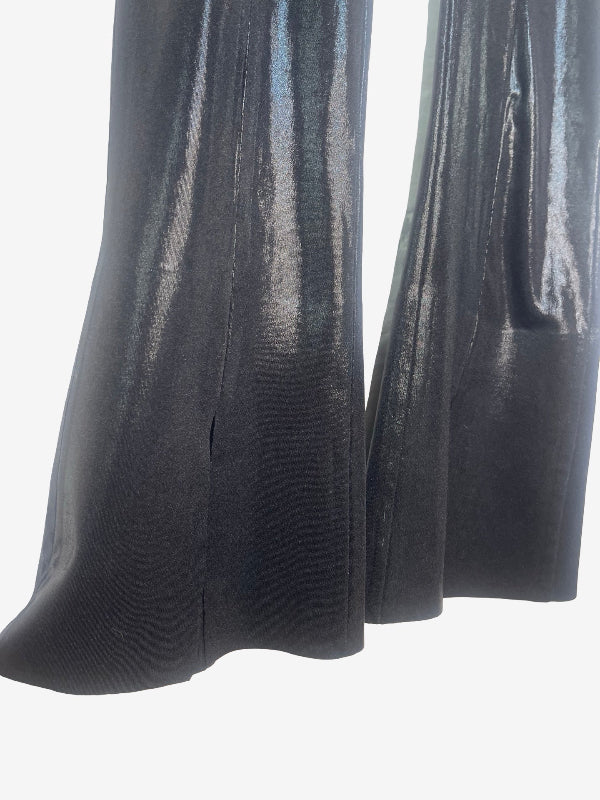 Close-up of a black flared pant leg with a glossy, metallic finish, showing the fabric texture and drape against a plain white background.