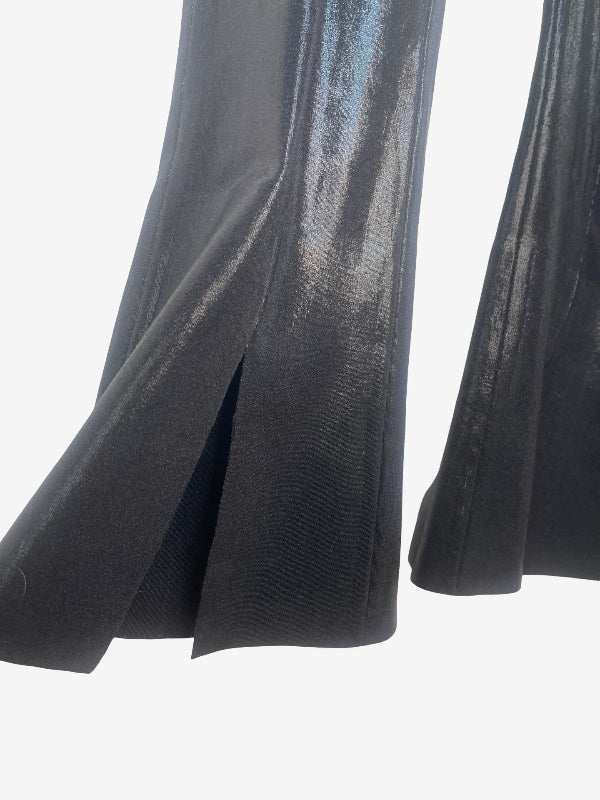 Close-up of a black flared pant with a vertical slit, showing a subtle metallic sheen against a light gray background.