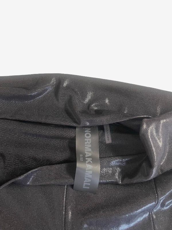 Close-up of a black metallic fabric garment with a visible interior label reading NORMA KAMALI.