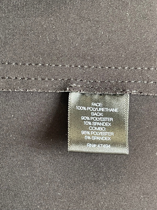 Close-up of a sewn-in fabric care label on a dark gray garment, showing material composition text including 100% polyurethane back, 90% polyester, 10% spandex, and 95% polyester, 5% spandex.