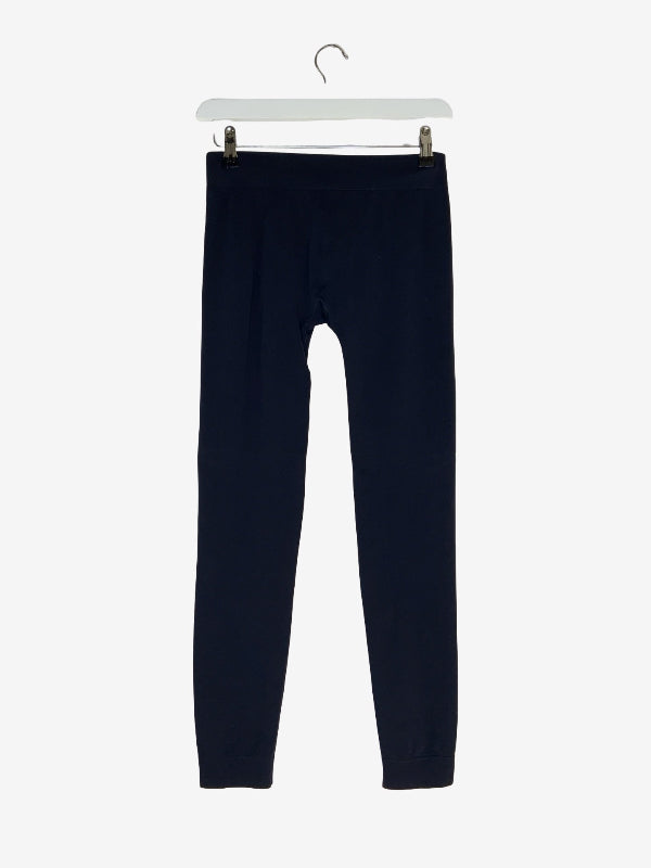 A pair of dark navy blue leggings hanging from a white plastic hanger with metal clips against a light gray background.