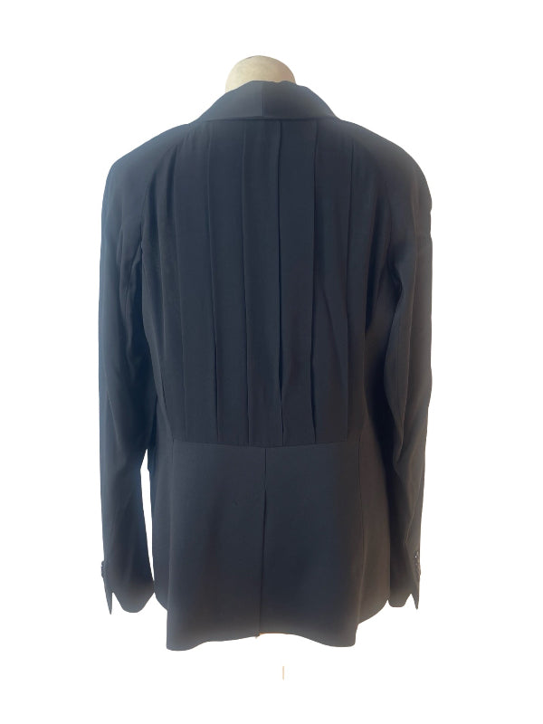 A black pleated tuxedo shown from the back, displayed on a mannequin torso against a plain white background.