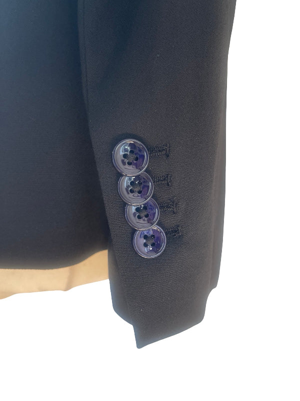 Close-up of a black suit jacket sleeve showing four black decorative button,, set against a bright white background.