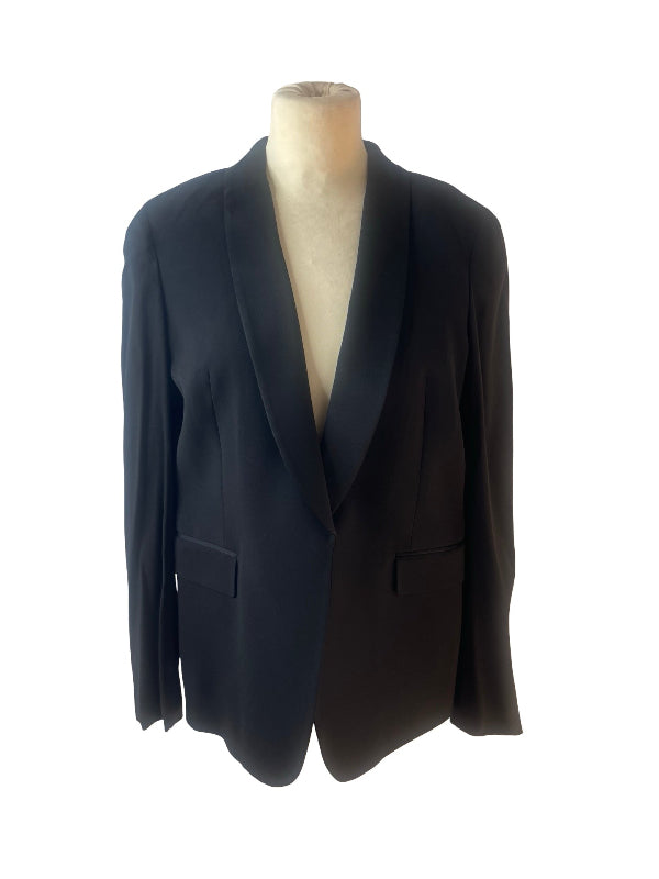 A black women's blazer with shawl lapels and flap pockets, displayed on a beige mannequin torso against a plain white background.