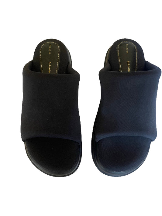 A pair of black slide sandals with wide, cushioned straps and a low platform sole, shown from a top-down view on a white background.