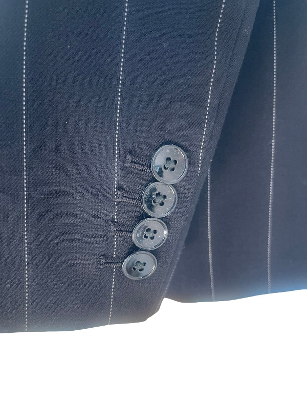 Close-up of a black pinstripe suit jacket sleeve showing four buttons and fine white vertical stripes.