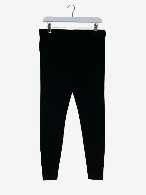 Black jodphurs hanging from a white plastic hanger against a light gray background.