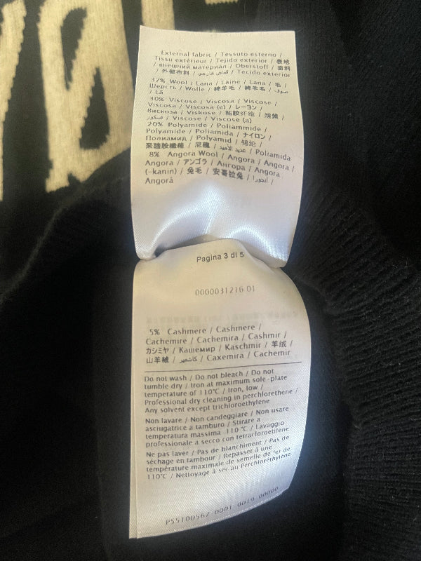 A close-up of a white paper tag with printed text laid on dark knit fabric.