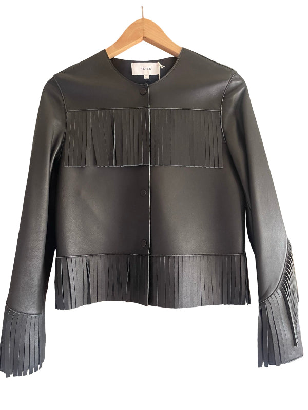 A black leather jacket with pleated fringe details on the chest, hem, and cuffs, hanging on a wooden hanger against a white background.