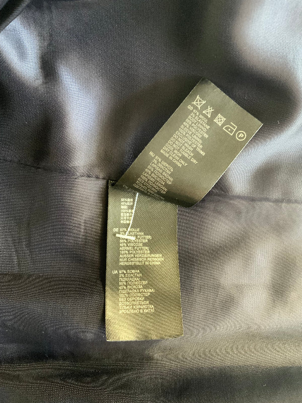 Close-up of two garment care and size tags sewn onto a black  fabric surface.