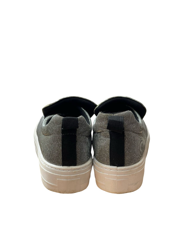 A pair of low-top slip-on sneakers shown from the back, featuring a gray silver upper, a black vertical strap, and a thick off-white platform sole.