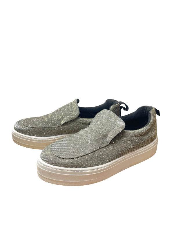 A pair of slip-on platform sneakers in a glittery silver material with beige soles and black lining, shown on a plain white background.