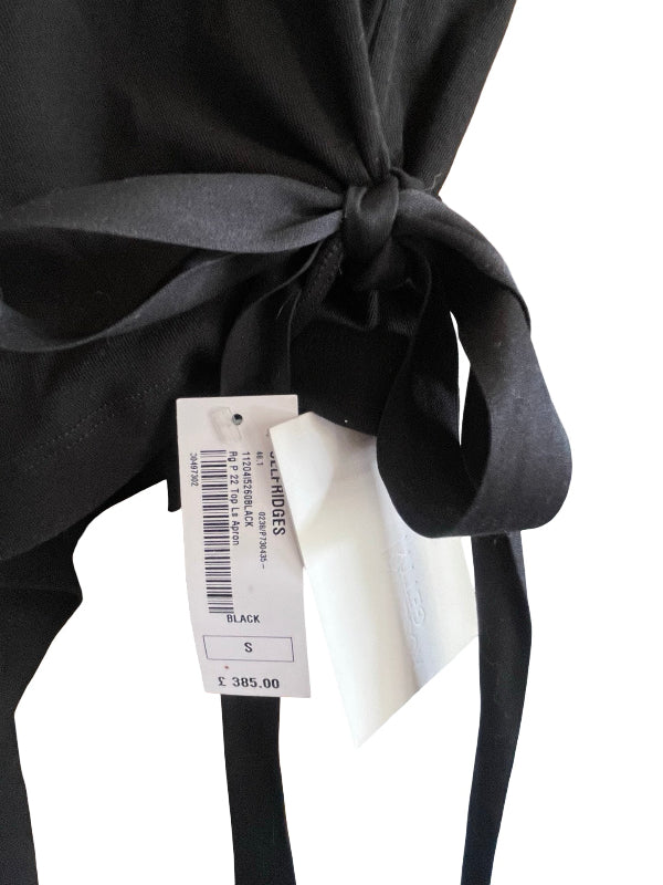 Close-up of a black garment tied in a bow with a white retail hangtag attached, photographed against a plain white background.