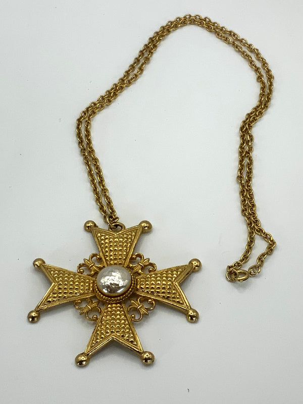 A gold-tone medieval-style cross pendant necklace with a textured star design and a central round white stone, shown on a plain white background.