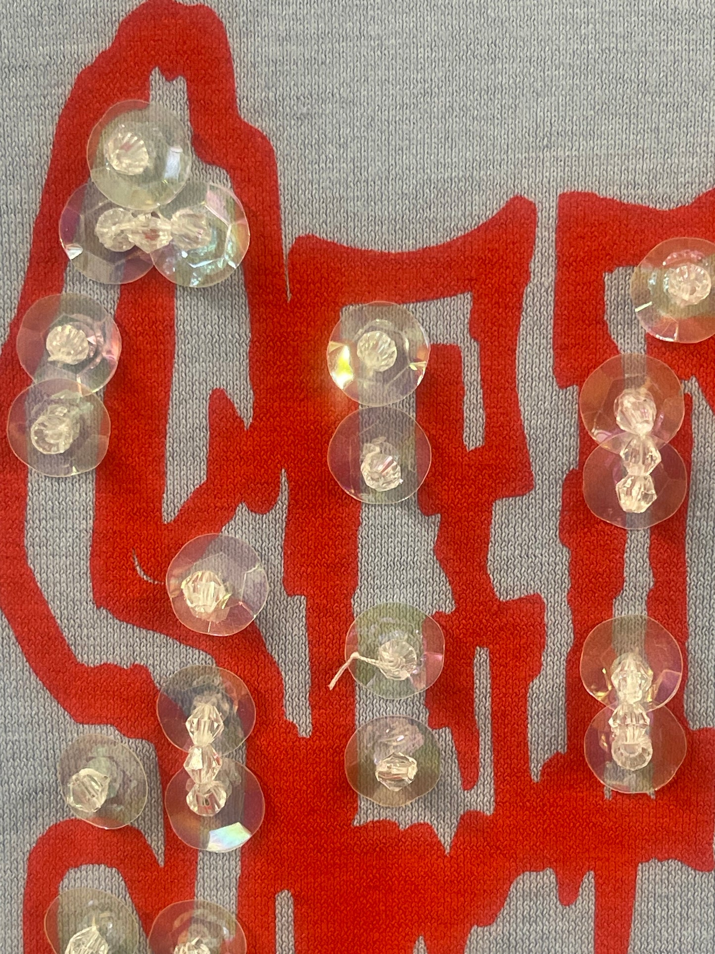 Several clear, iridescent plastic buttons arranged on a gray blue fabric background with a large red Chinese character printed underneath.