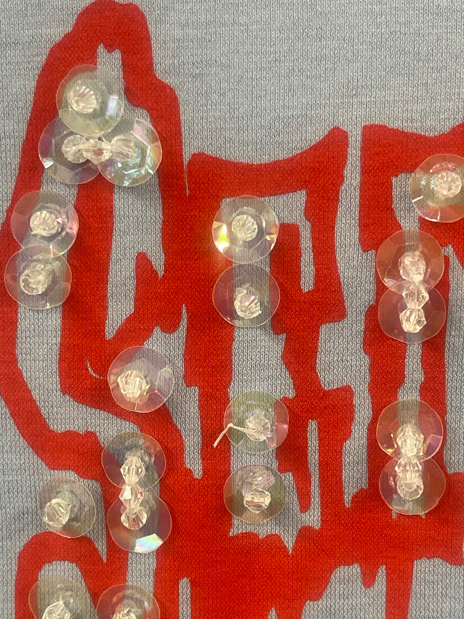 Several clear, iridescent plastic buttons arranged on a gray blue fabric background with a large red Chinese character printed underneath.