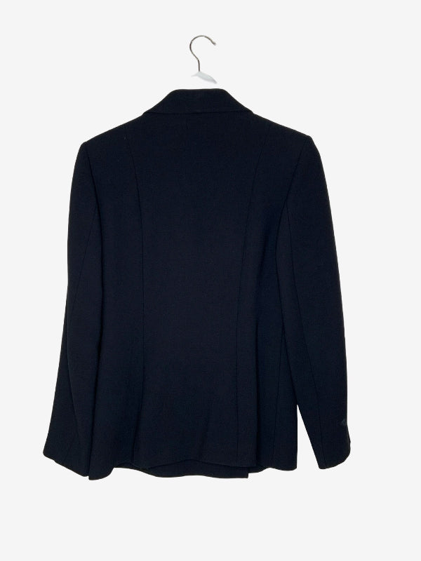 A black blazer jacket hanging on a white hanger against a light gray background.