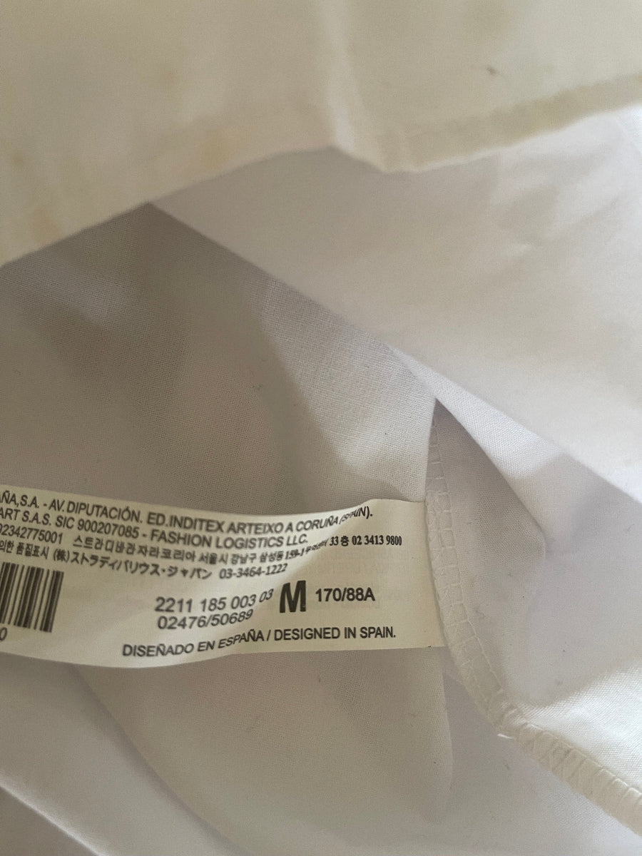 Close-up of a white garment's interior tag showing size information and printed text, photographed against the white fabric.