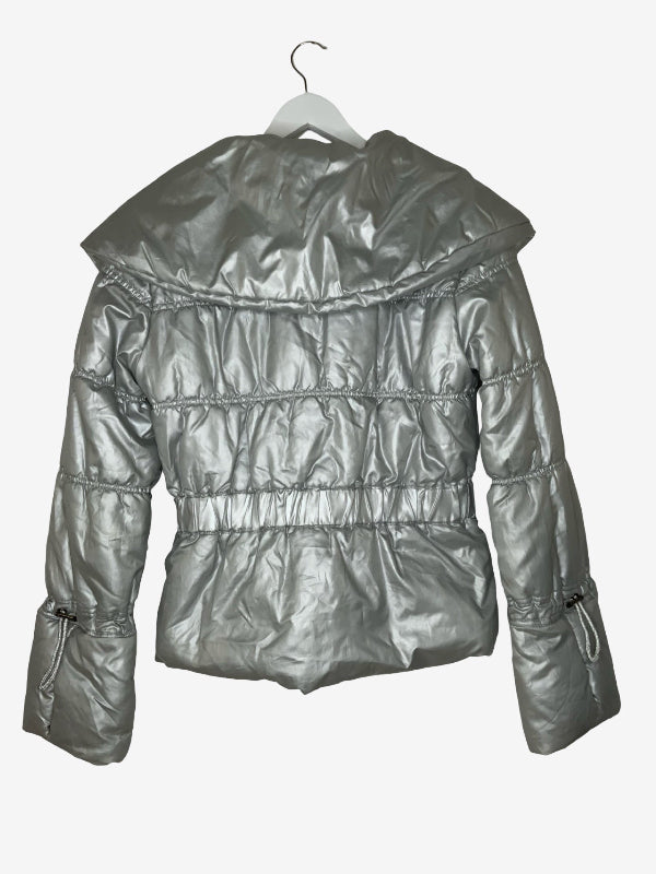 A metallic silver puffer jacket with a wide collar and horizontal quilting, hanging on a white hanger against a light gray background.