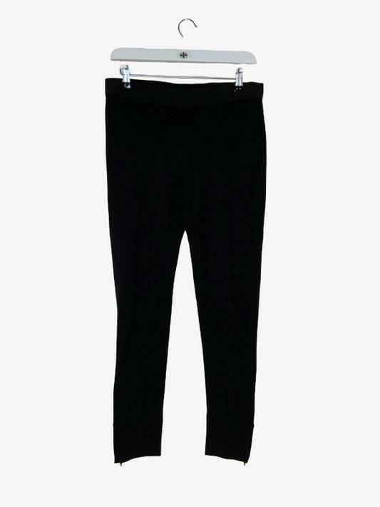 Black cropped leggings hanging from a white hanger against a light gray background.