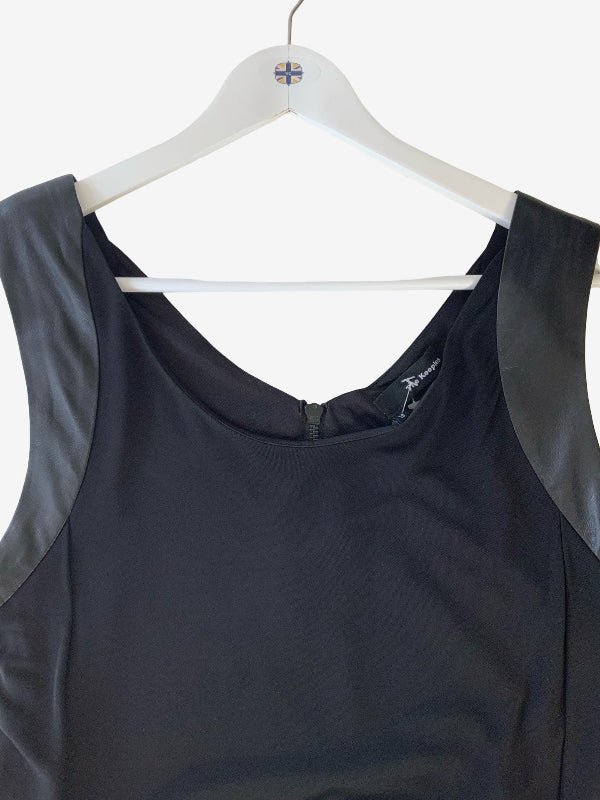 A sleeveless black dress with contrasting leather shouldet panels, hanging on a white plastic hanger against a plain white background.